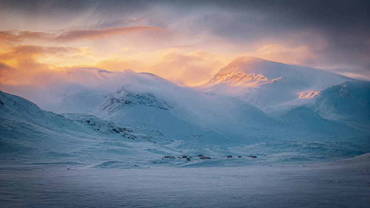 Majestueuze landschappen met besneeuwde bergen onder een kleurrijke hemel, die uitnodigen tot een uitstapje naar Lapland.