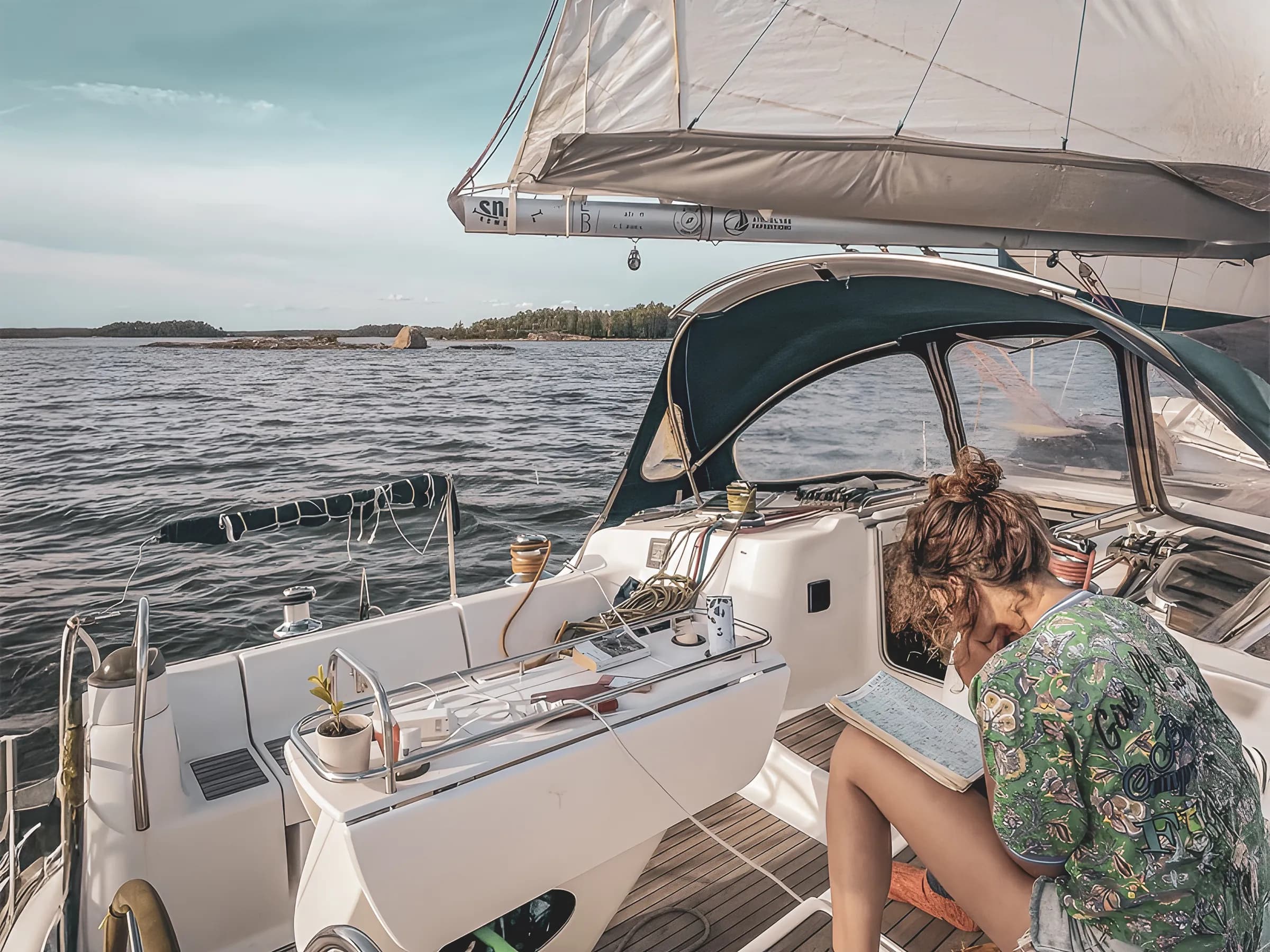 Une personne assise sur un voilier explore un carnet, entourée d'une mer paisible et de paysages aquatiques.