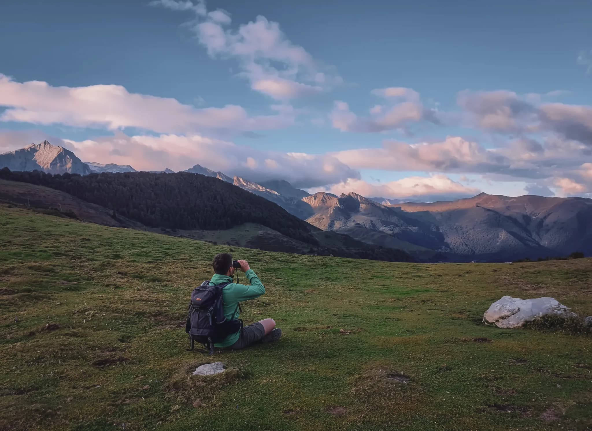 Un randonneur observe les majestueuses montagnes des Pyrénées au coucher du soleil.