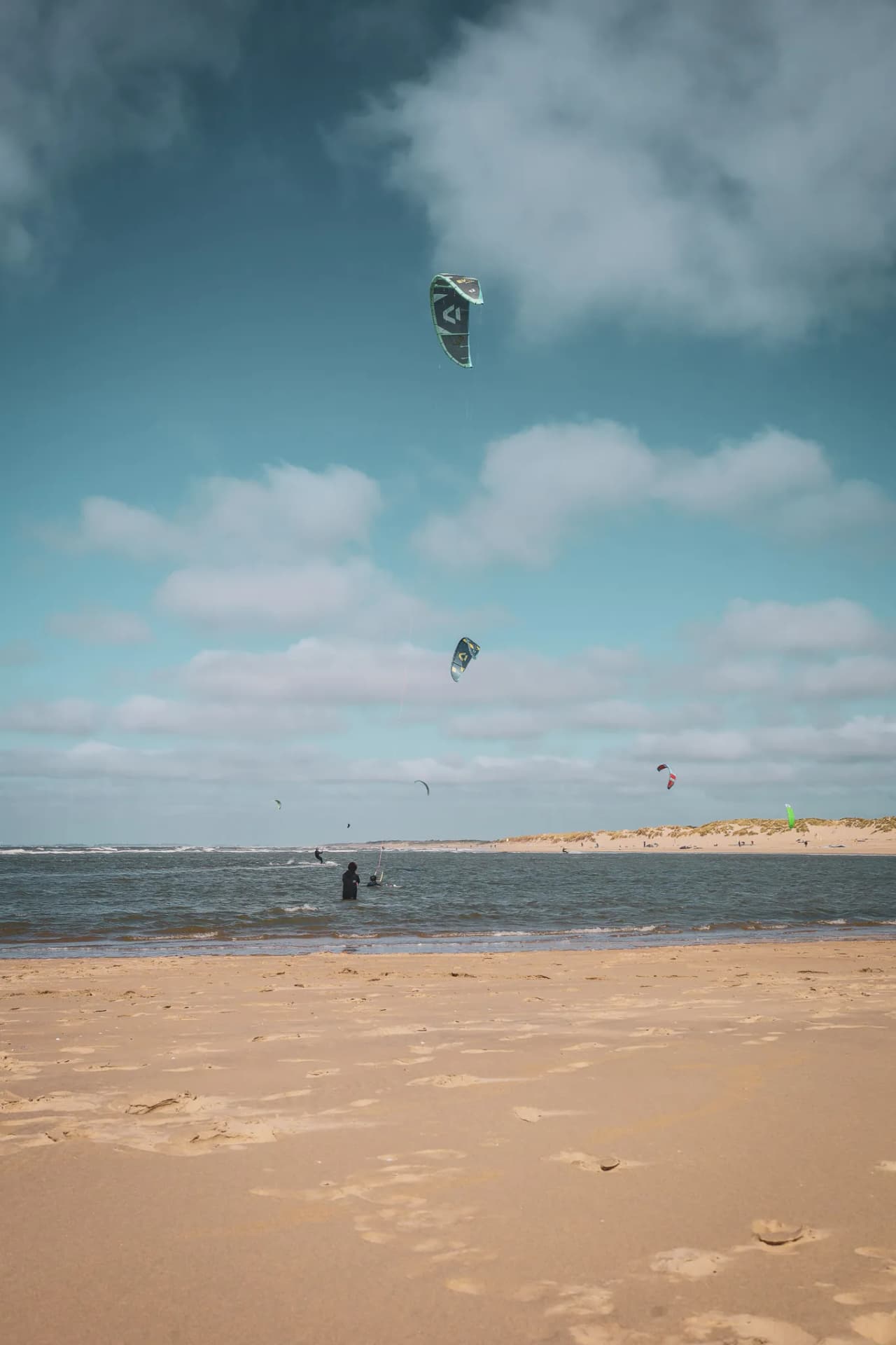Beach in Zeeland, colourful kites in the sky, kitesurfing atmosphere and golden dunes.