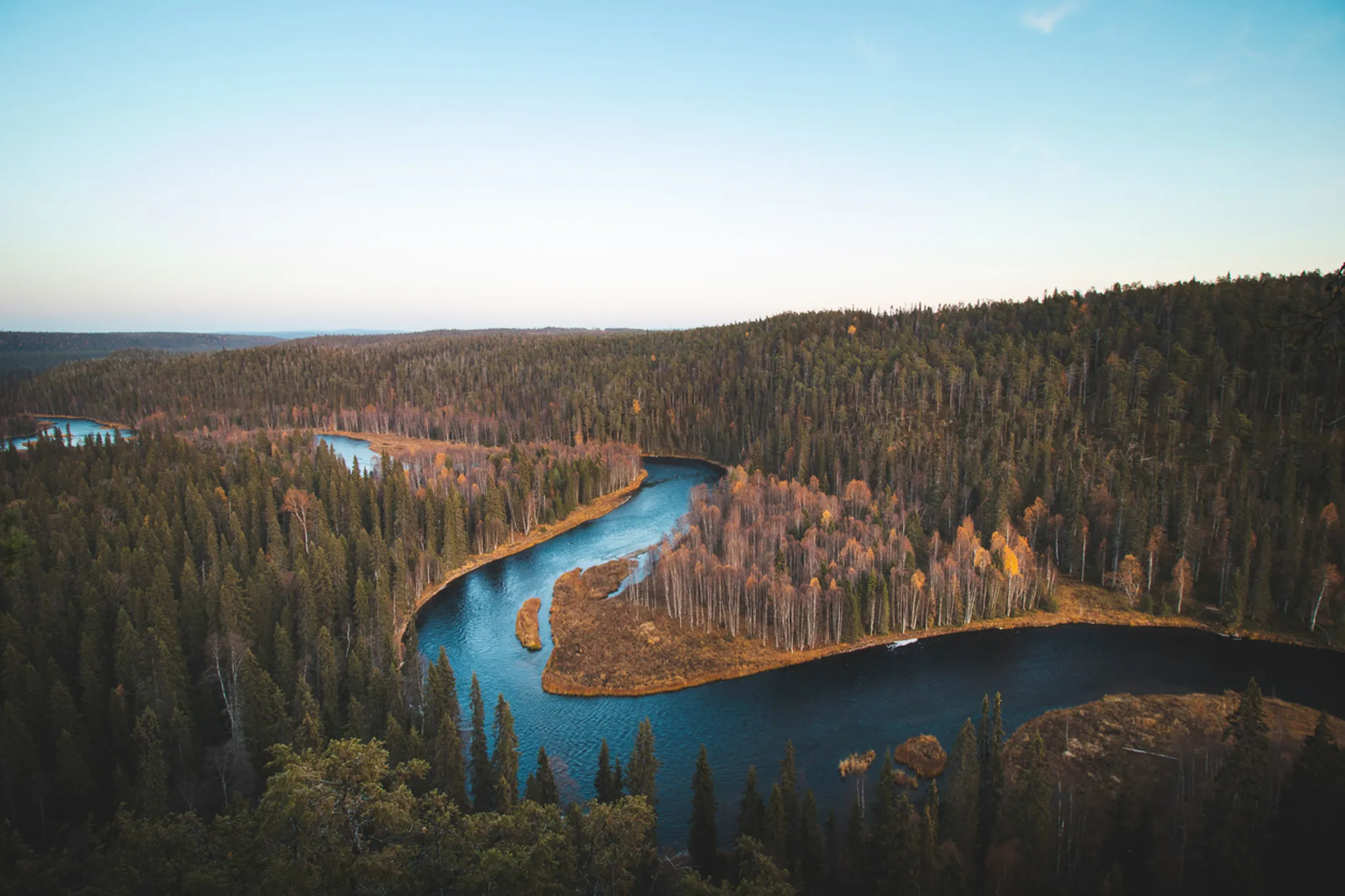 Winding rivers surrounded by lush green forests in Lapland, an invitation to outdoor adventure.
