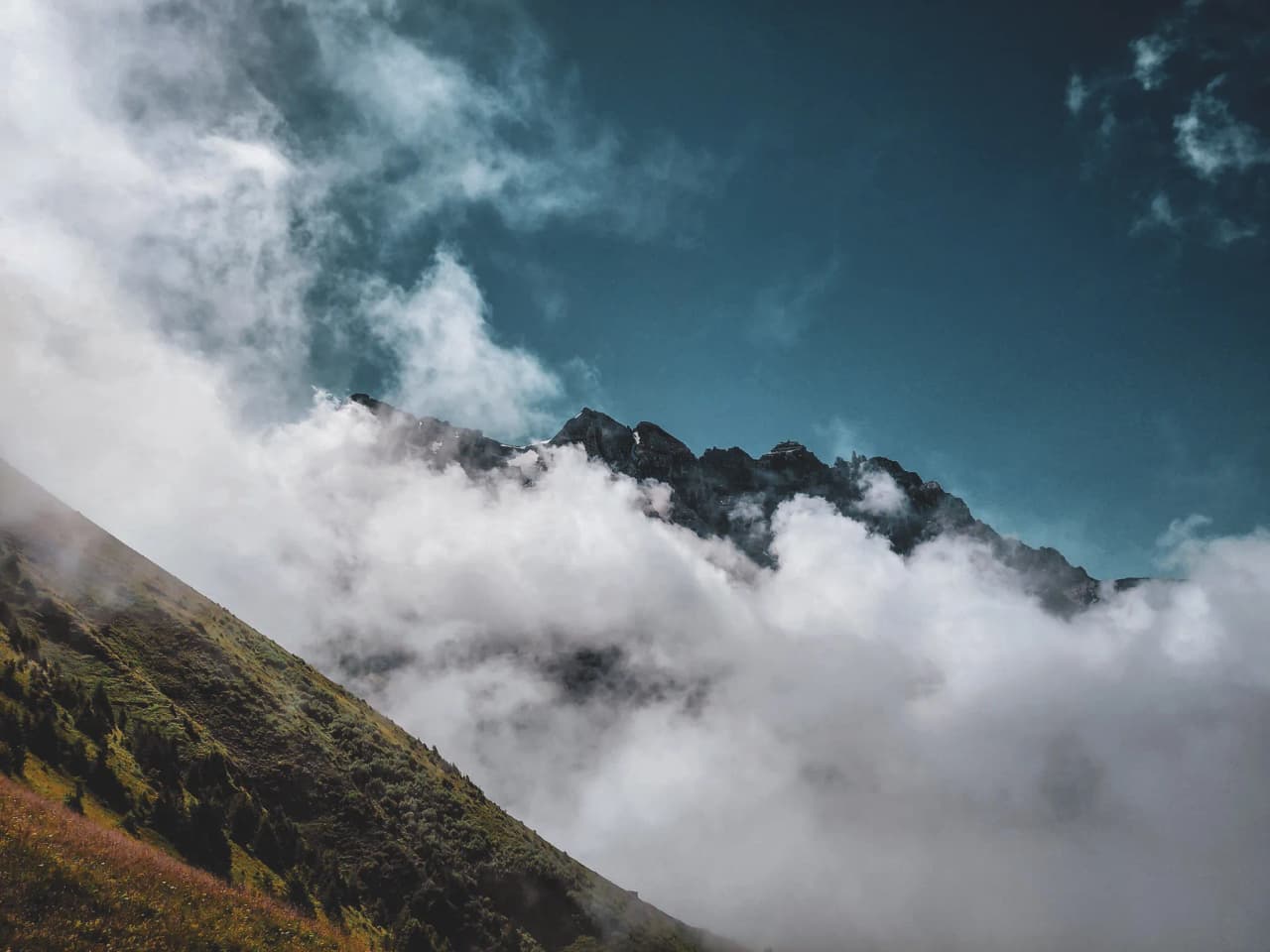 Majestic mountains emerge from the clouds, offering an enchanting Alpine landscape.