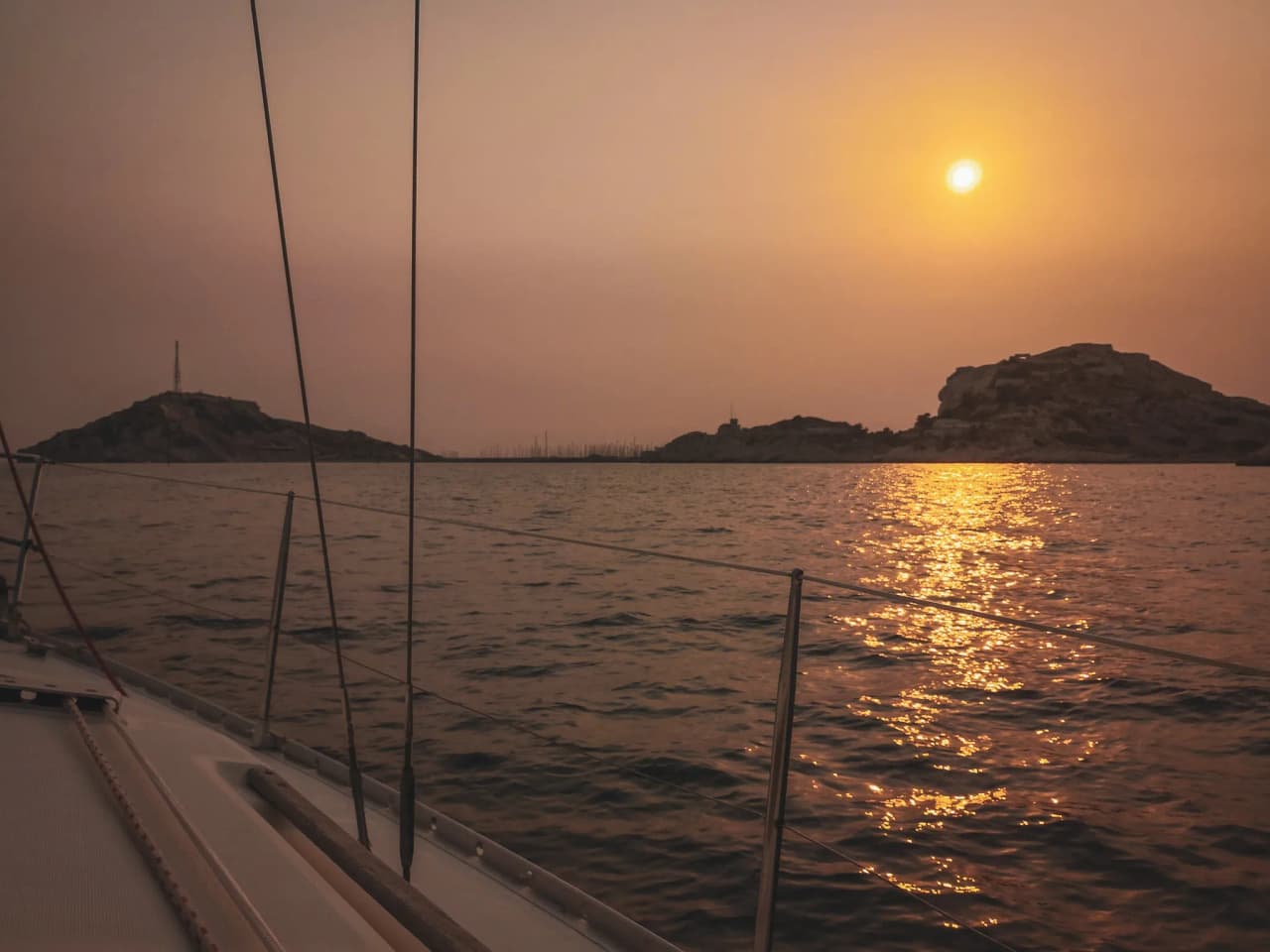 Coucher de soleil doré sur les Calanques, avec des falaises et des eaux calmes en horizon.