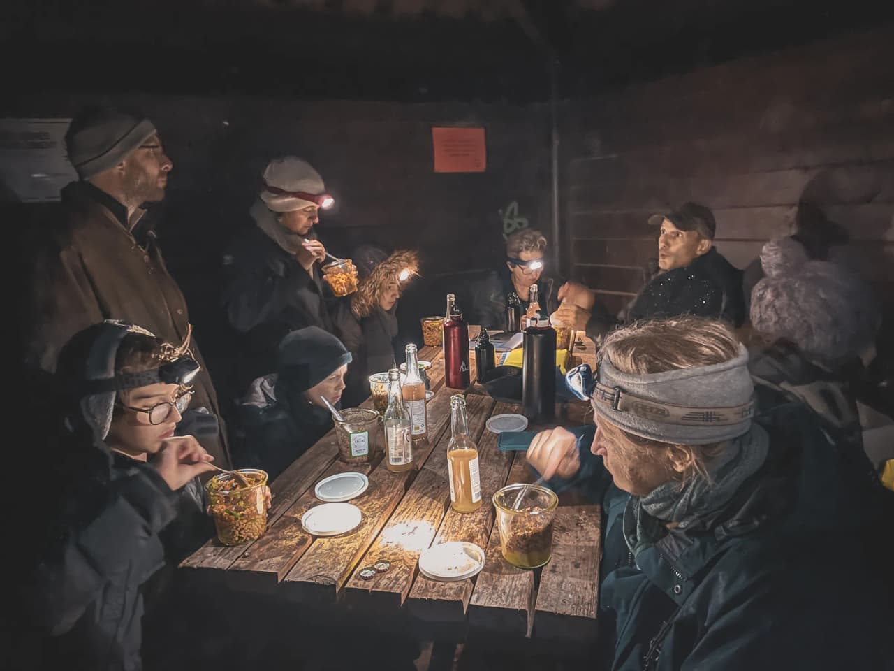 Groupe de personnes partageant un repas convivial en forêt, préparant l'écoute du brame du cerf.