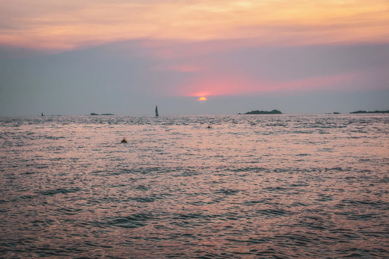 Zonsondergang over de oceaan, zeilboot in silhouet, de serene sfeer van wild Bretagne.