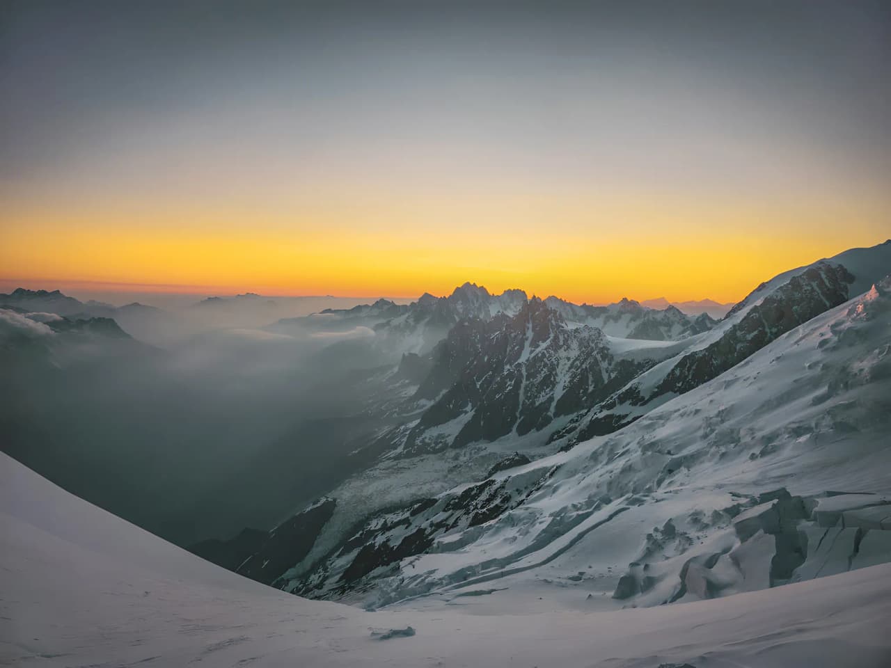 Sunset over the majestic Alps, with snow-capped peaks and mysterious clouds.
