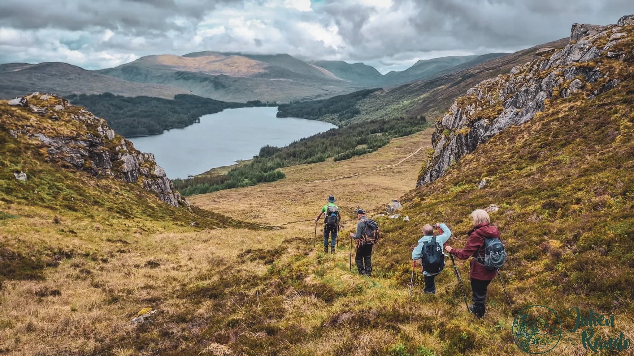 Een groep wandelaars verkent het woeste landschap van de Highlands, met een meer op de achtergrond.