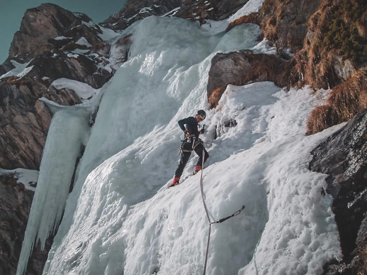 Un alpiniste en pleine ascension sur une cascade de glace dans les Alpes italiennes.