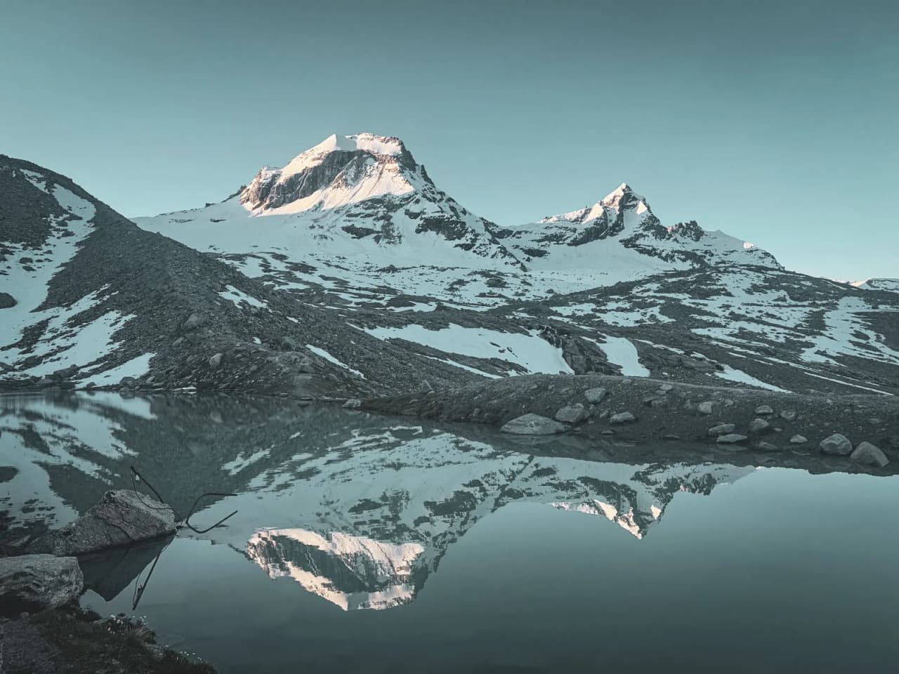 The majestic landscape of Gran Paradiso, snow-capped mountains reflected in a serene lake.