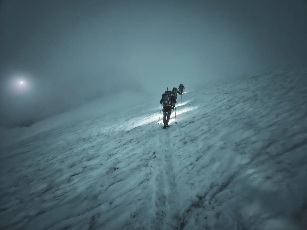 Mountaineers ascending a glacier through a mysterious fog, an atmosphere of adventure.