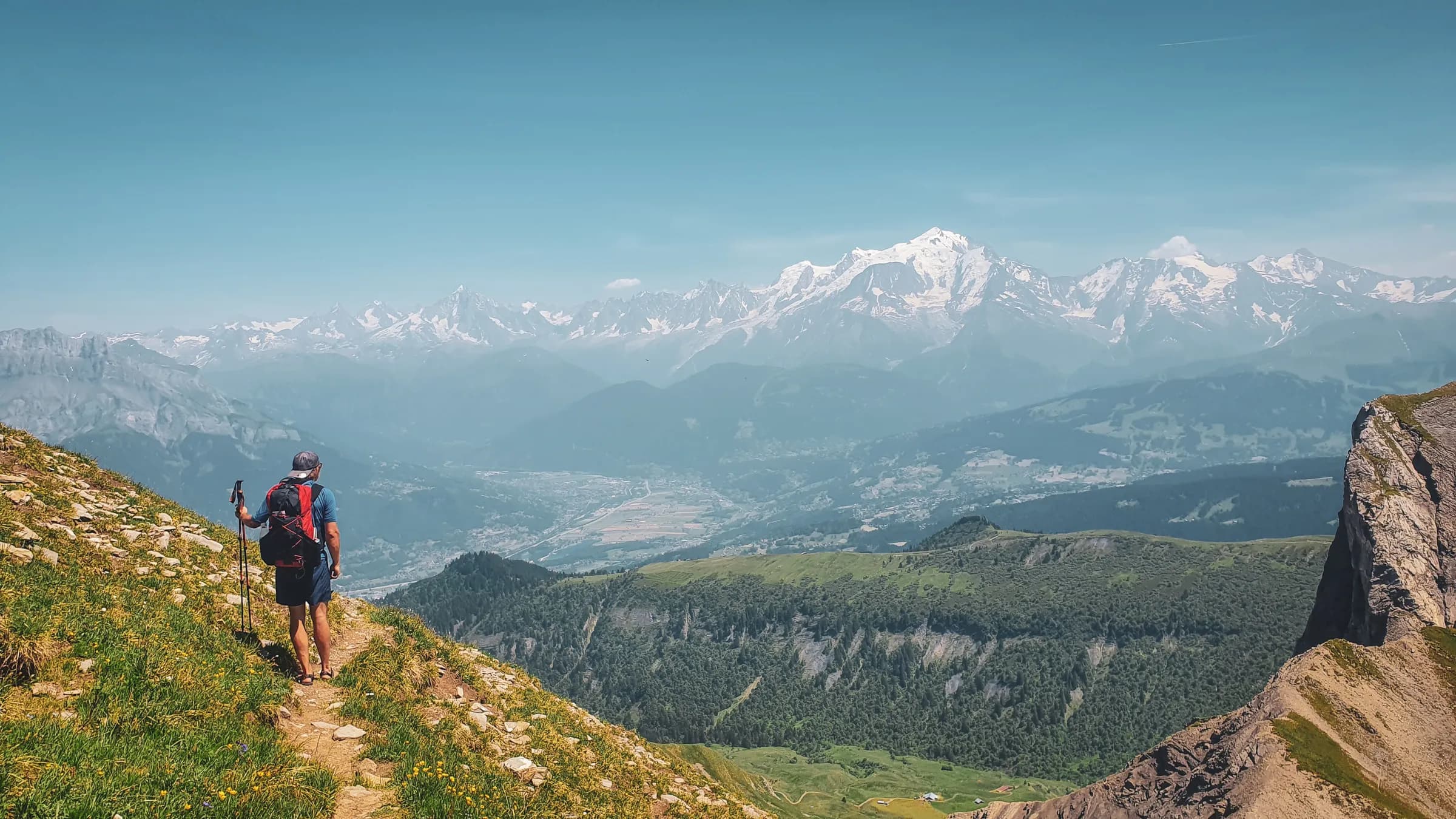 A hiker contemplates the peaks of the Aravis mountains, surrounded by breathtaking Alpine scenery.