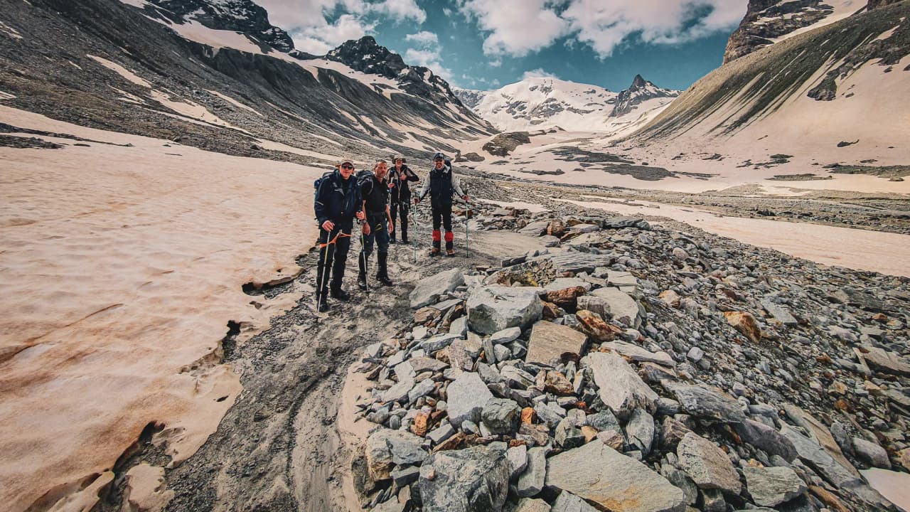 A group of hikers on an Alpine glacier, surrounded by majestic Alpine scenery.