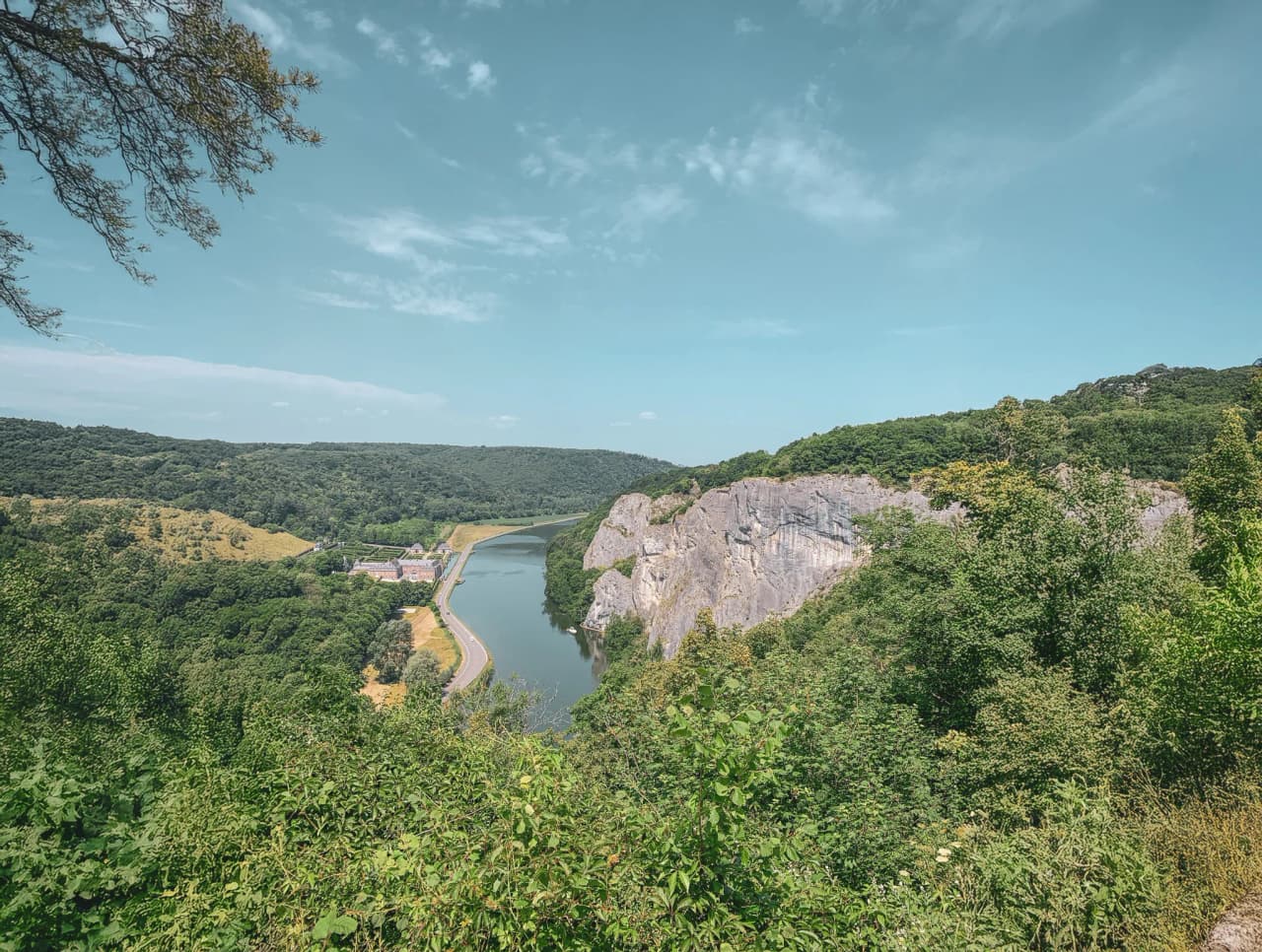 Panoramic view of a green valley with a river, surrounded by majestic cliffs.