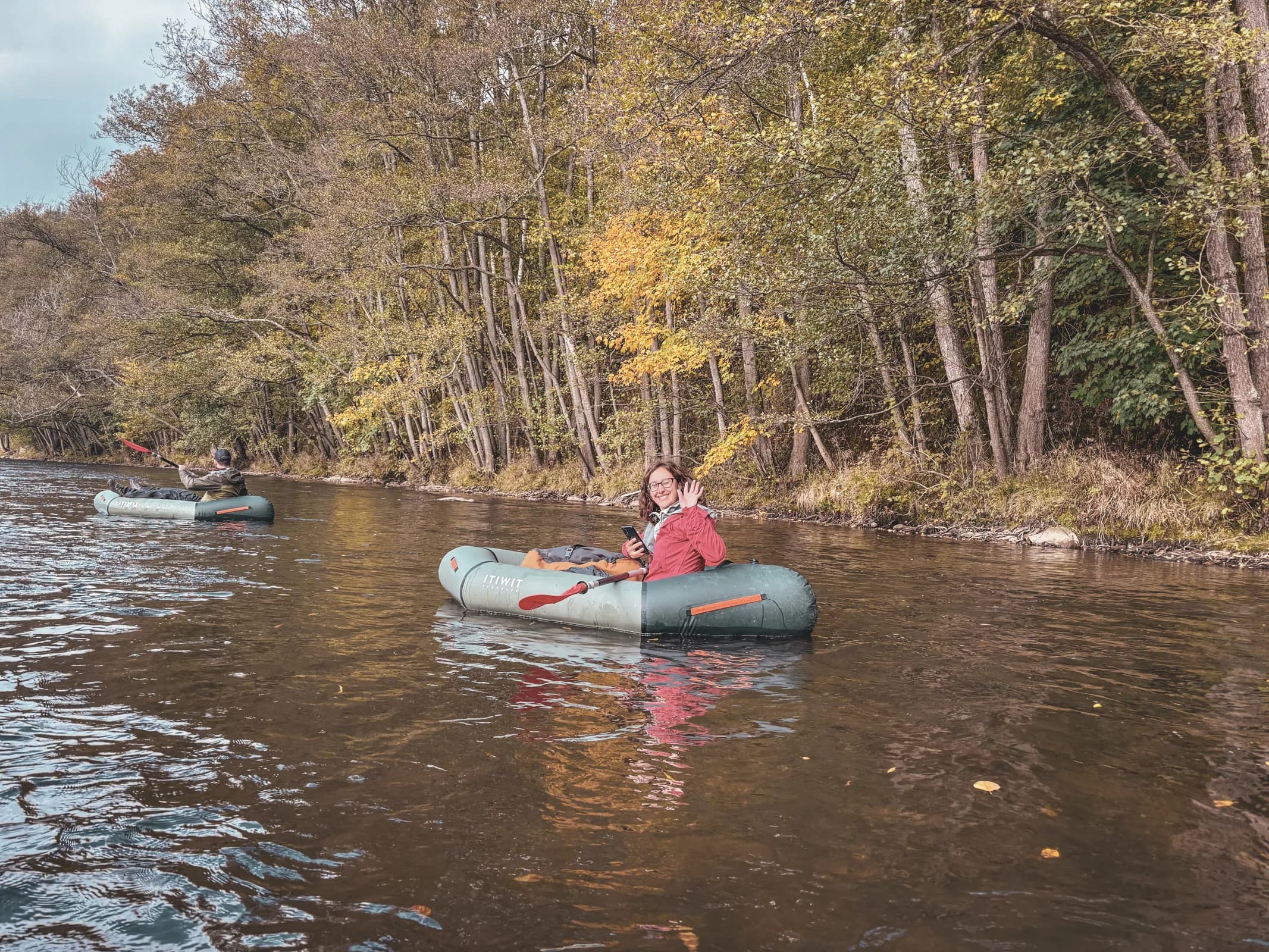 A packraft group on a river surrounded by beautiful golden forests in the Ardennes.