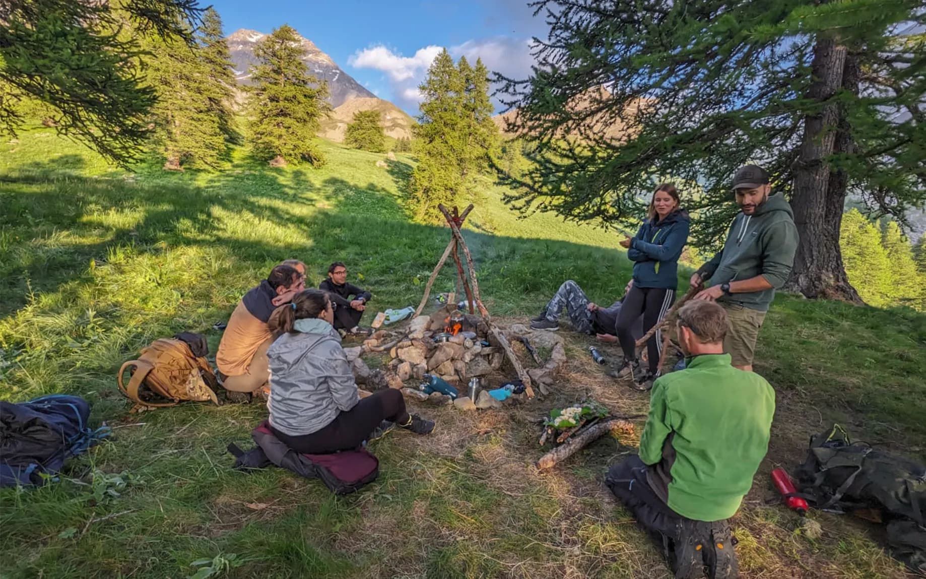 A group in the great outdoors around a campfire, learning how to survive in the mountains.