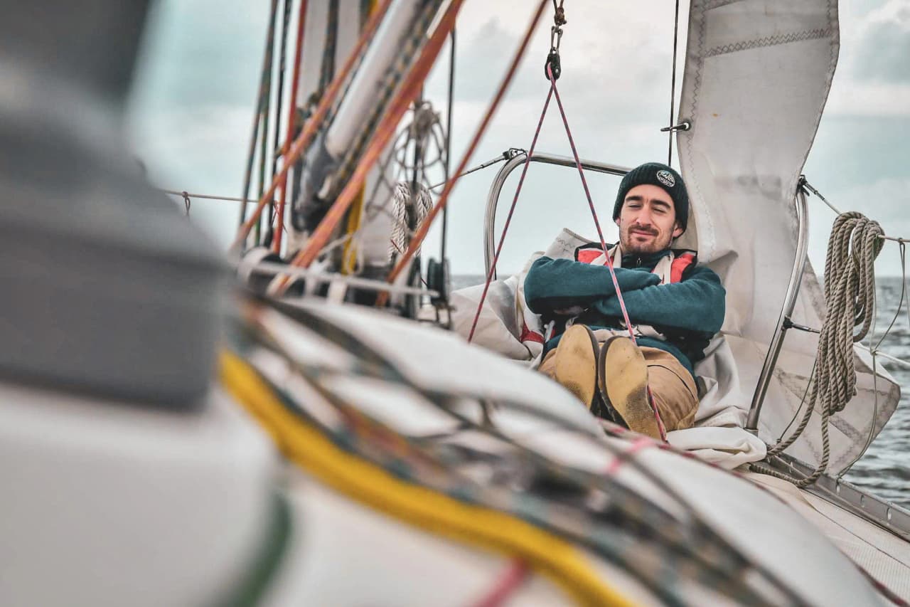 A relaxed sailor on a sailing boat, enjoying the waves and a serene atmosphere at sea.