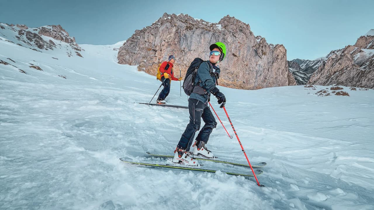 Two skiers on a glacier, surrounded by breathtaking mountain scenery.