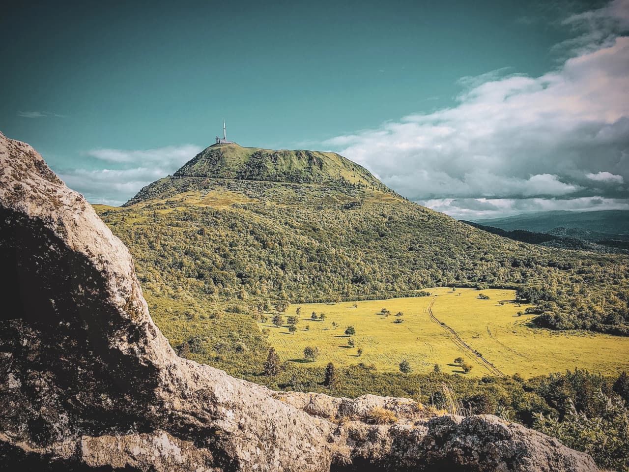 Vue panoramique des volcans d'Auvergne, avec le Puy de Dôme en toile de fond verdoyante.