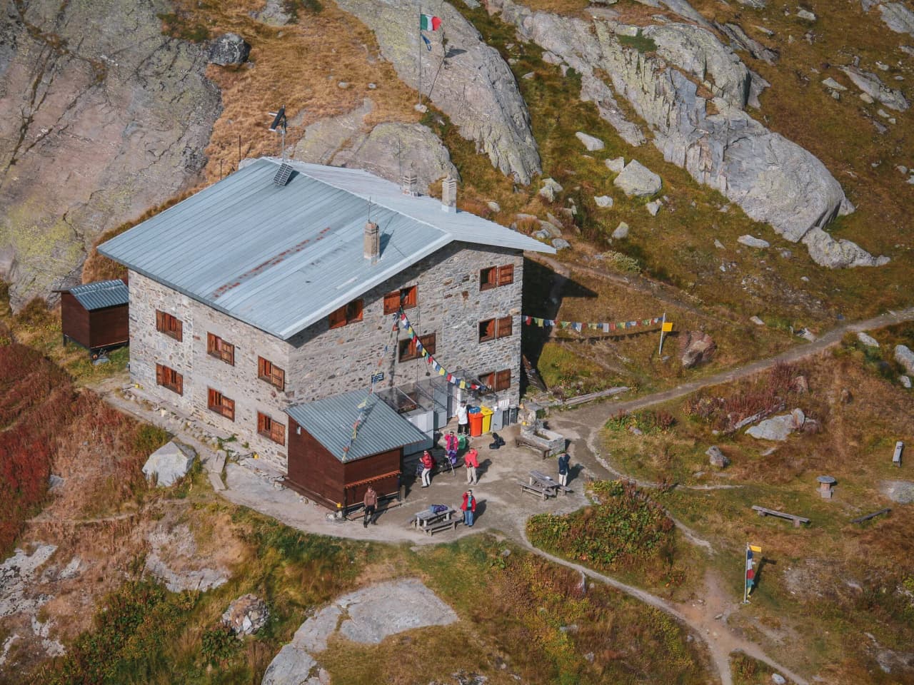 Chalet en pierre au cœur des Alpes, entouré d'une nature sauvage et colorée, invitation à l'aventure.