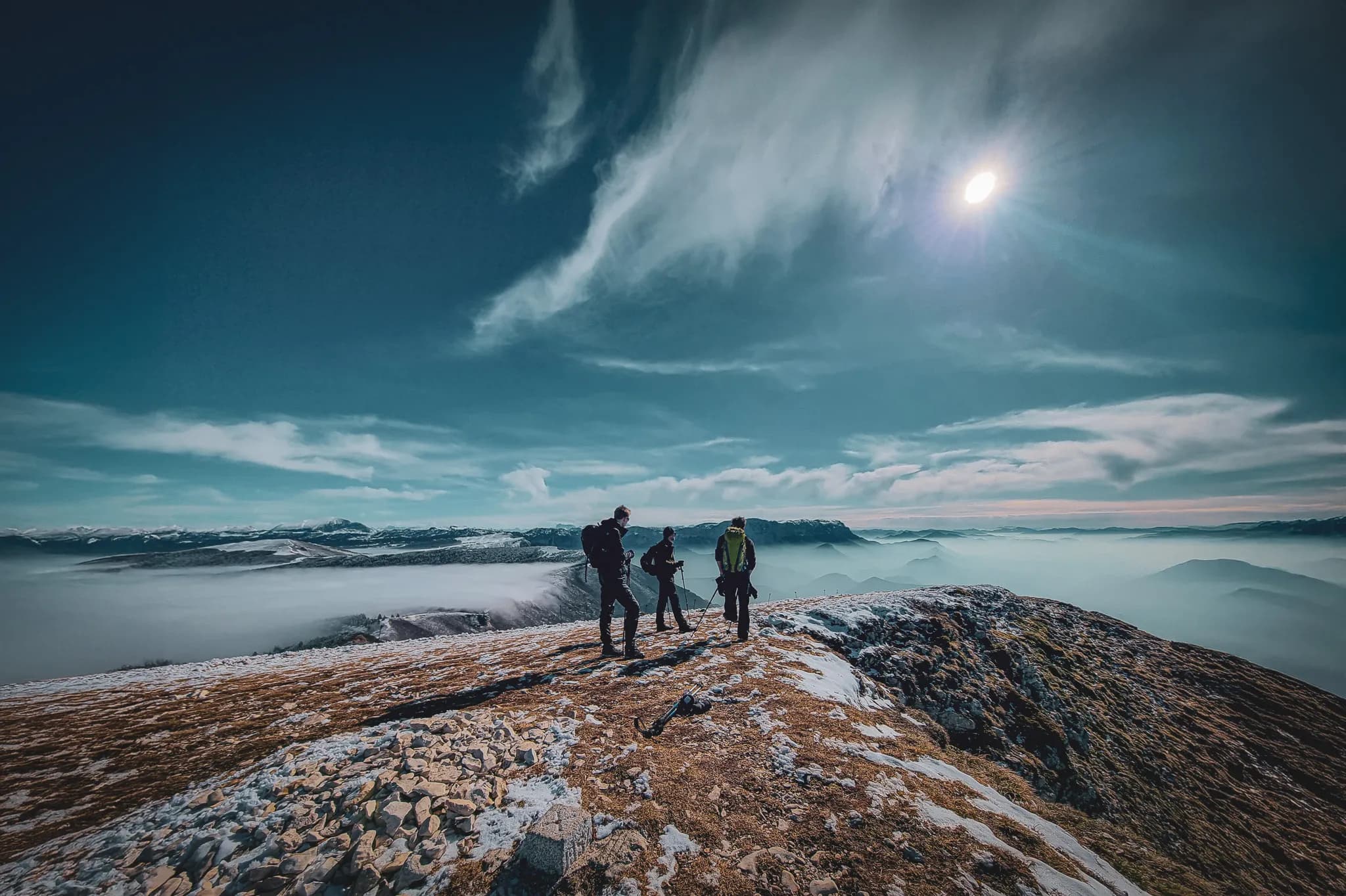 Three adventurers on top of a mountain in the Vercors, with breathtaking scenery and blue skies.