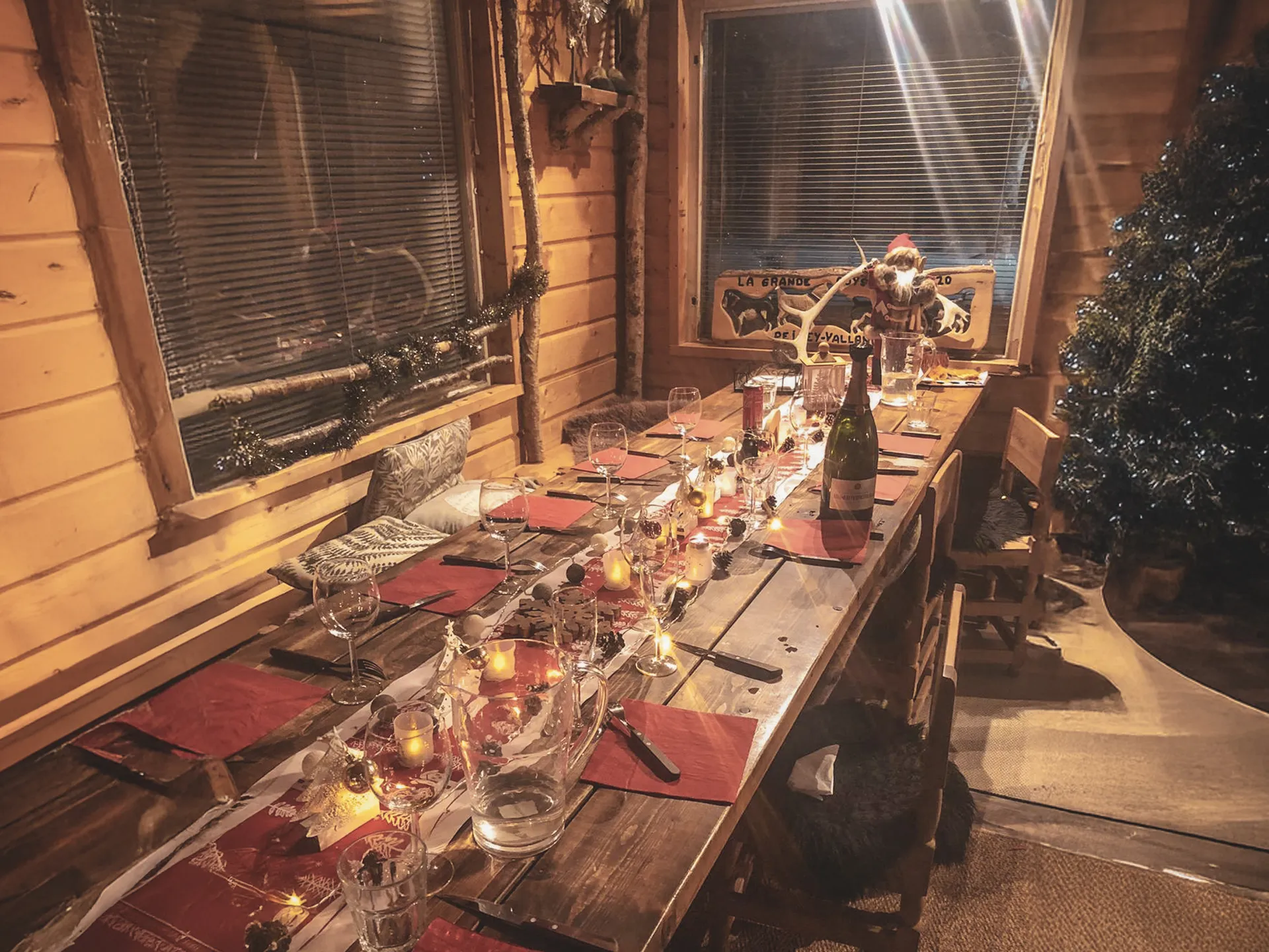 Table chaleureusement décorée avec des lumières et des couverts, dans une cabin en Laponie.