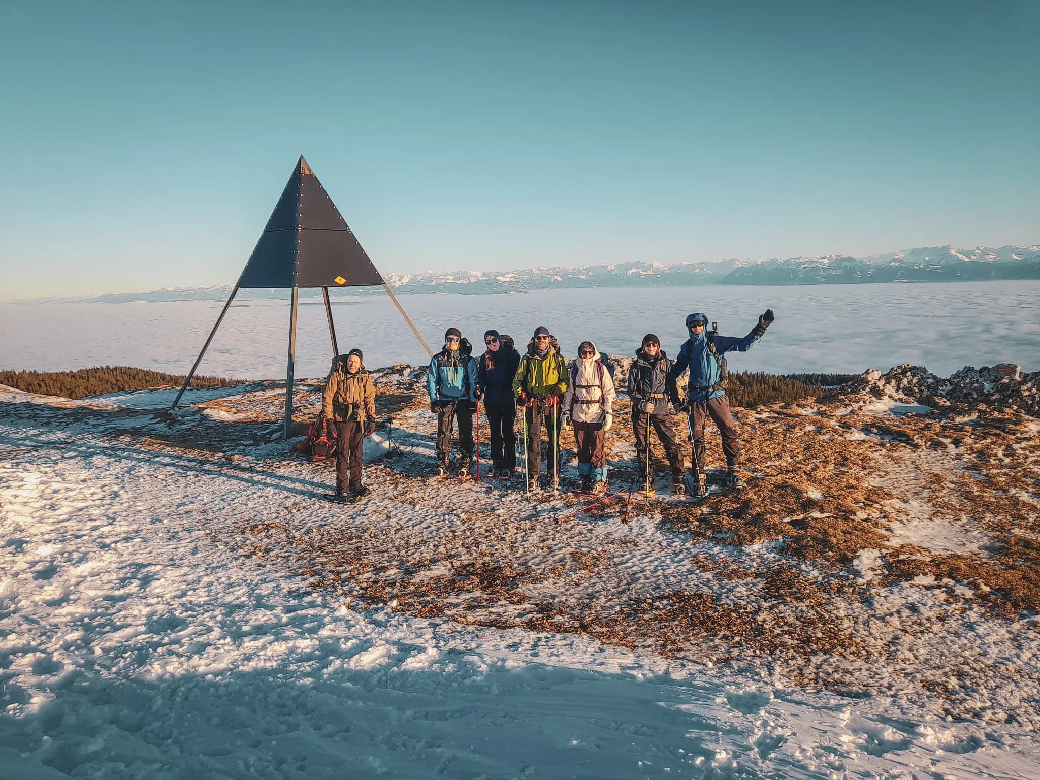 Een groep avonturiers op sneeuwschoenen, op de top van een besneeuwde berg, met een panoramisch uitzicht.