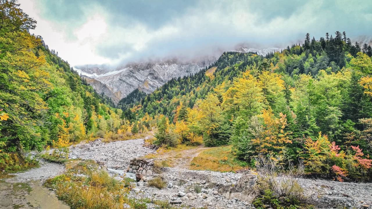 Een betoverend berglandschap, met herfstkleurige bossen en majestueuze bergtoppen.