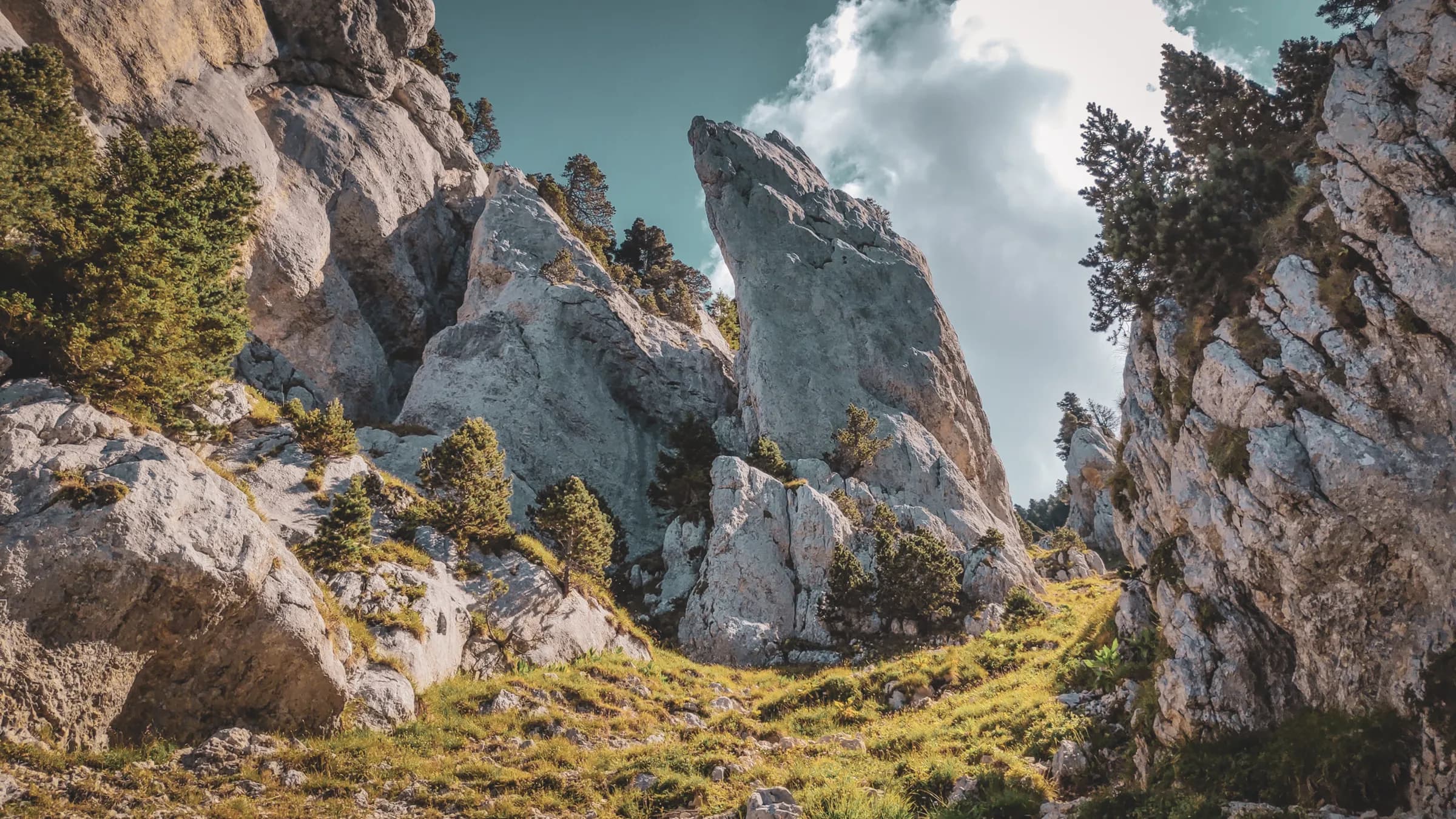 Des rochers majestueux et verdoyants sous un ciel bleu, invitation à explorer la nature préservée.