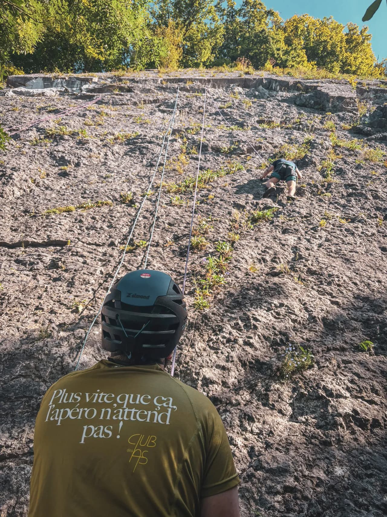 A climber tackles a sunny cliff during an introductory climbing course in Belgium.