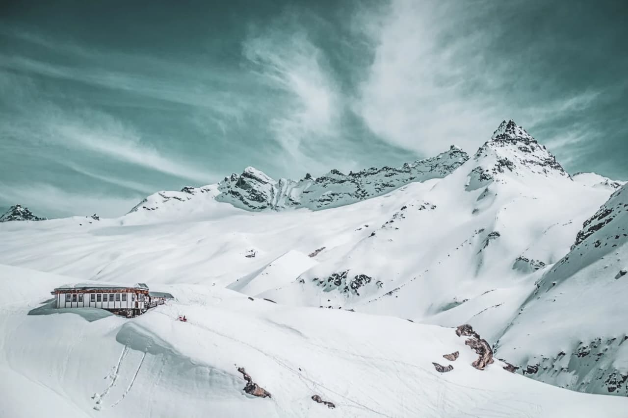 Spectacular Alpine scenery with glaciers, a snow-covered Mountain hut and snow-capped peaks.