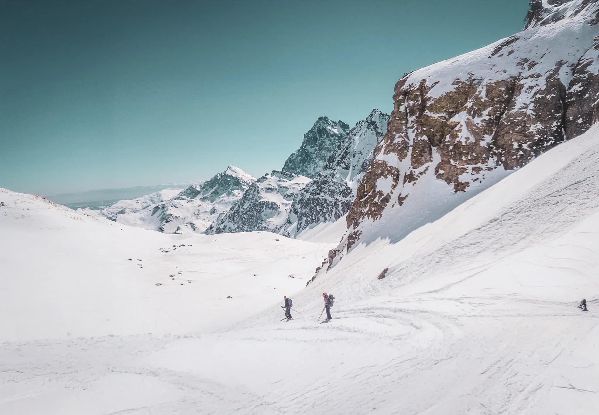 Randonneurs glissant sur la neige immaculée, sommets majestueux en toile de fond. Évasion alpine.