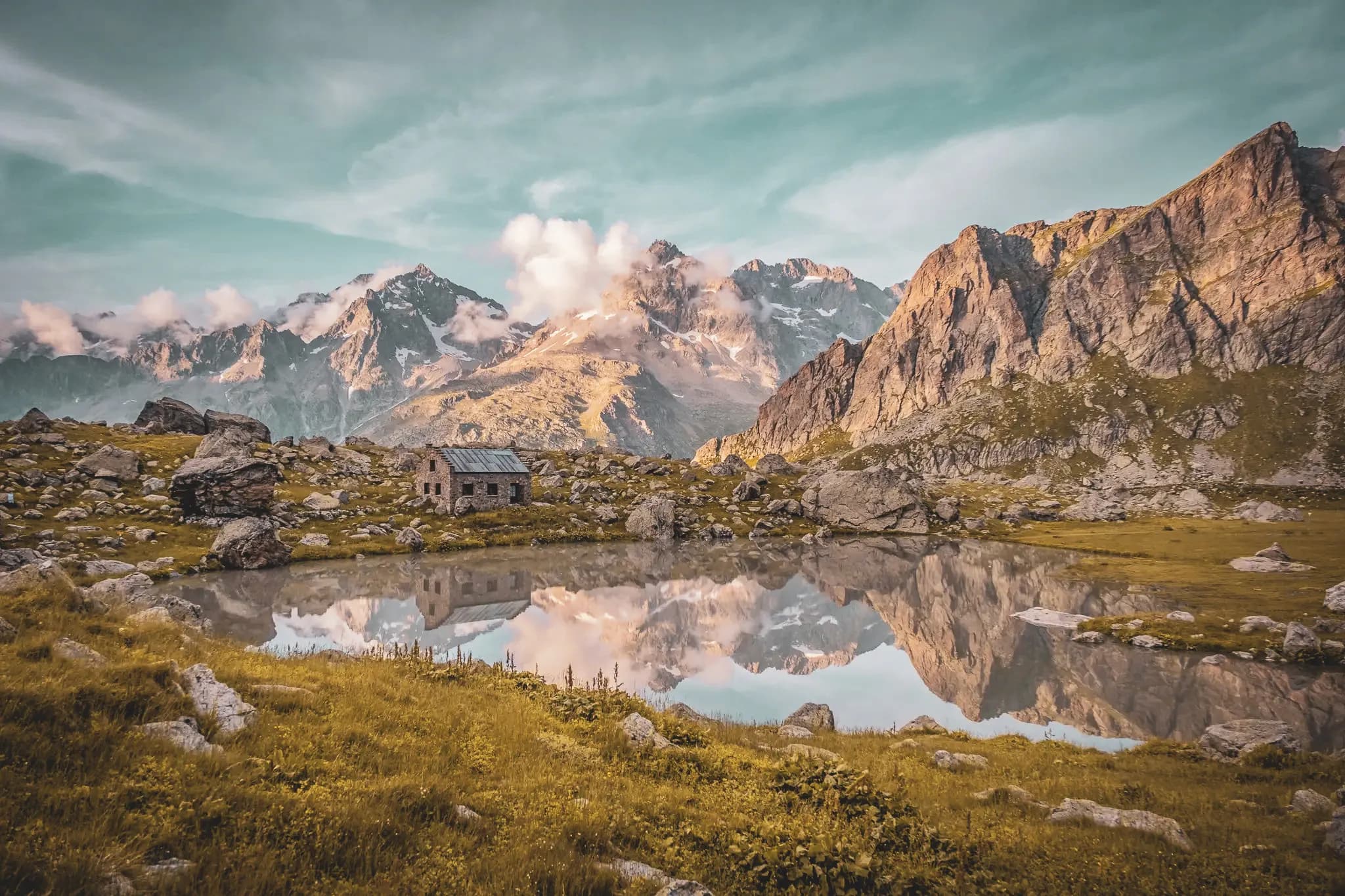 Een betoverende weerspiegeling van de bergen in een vredig meer, omringd door weiden en een oud chalet.