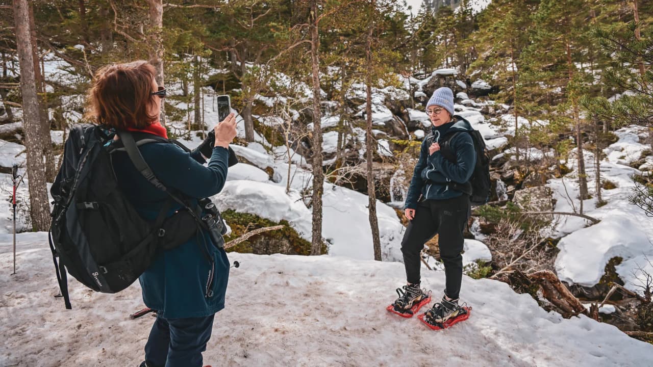 Two hikers on snowshoes take a break in a snow-covered landscape in the Pyrenees.