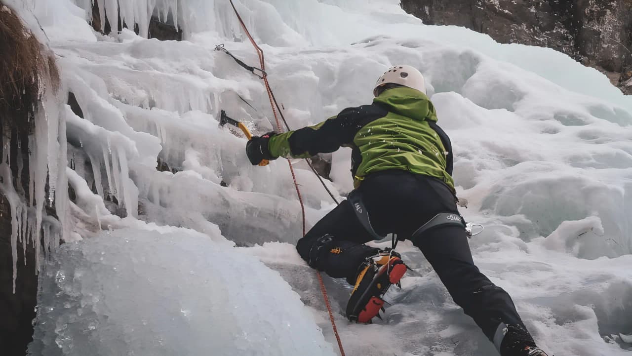 Un alpiniste escalade une cascade de glace, entouré par les majestueuses Alpes italiennes.