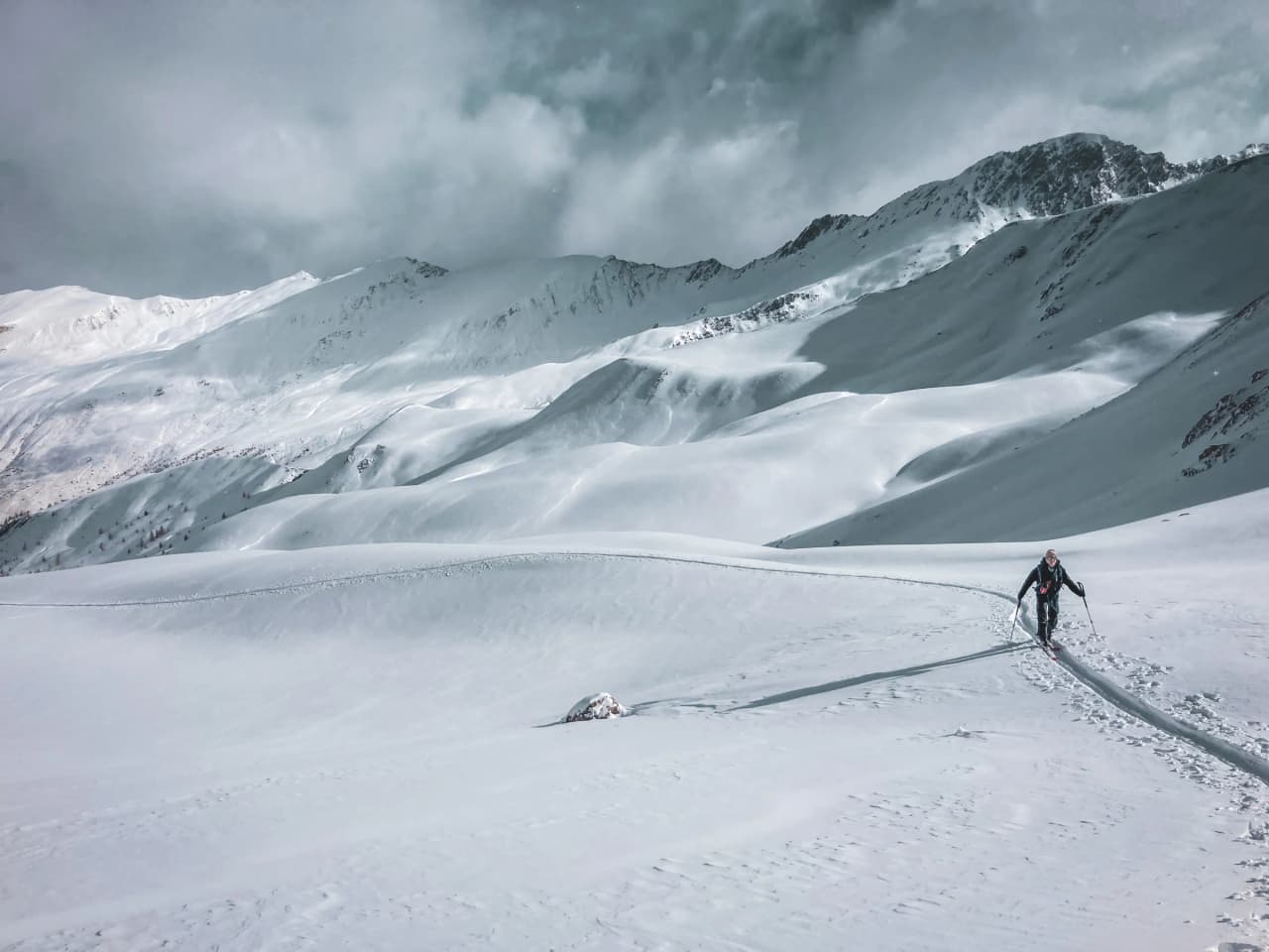 Un skieur solitaire arpente des paysages enneigés majestueux, au cœur des crêtes du Queyras.