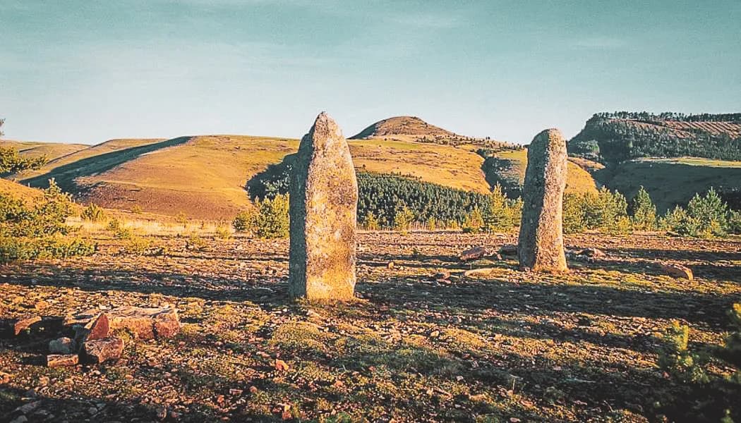 Deux menhirs se dressent majestueusement sur un paysage verdoyant, invitant à l'exploration.