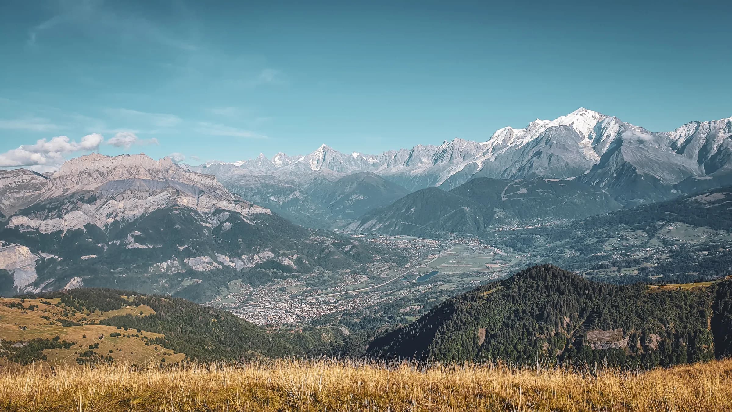 Panoramic views of the Aravis mountains, a green valley and blue skies that invite adventure.