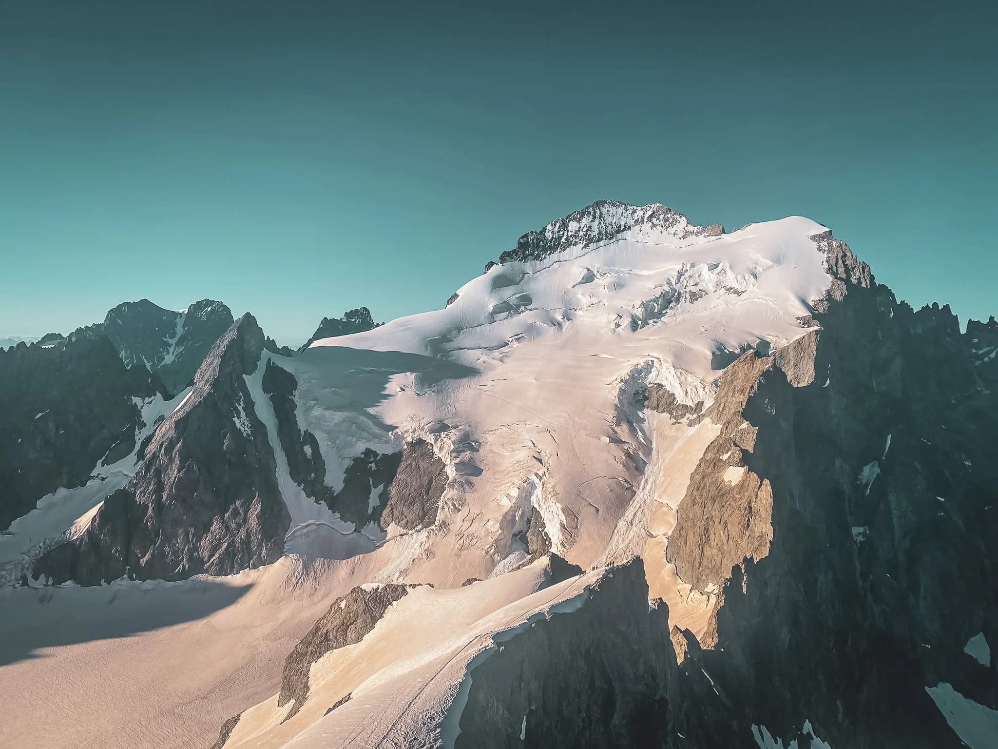 Paysage majestueux des Ecrins, sommets enneigés et glaciers éblouissants sous un ciel turquoise.