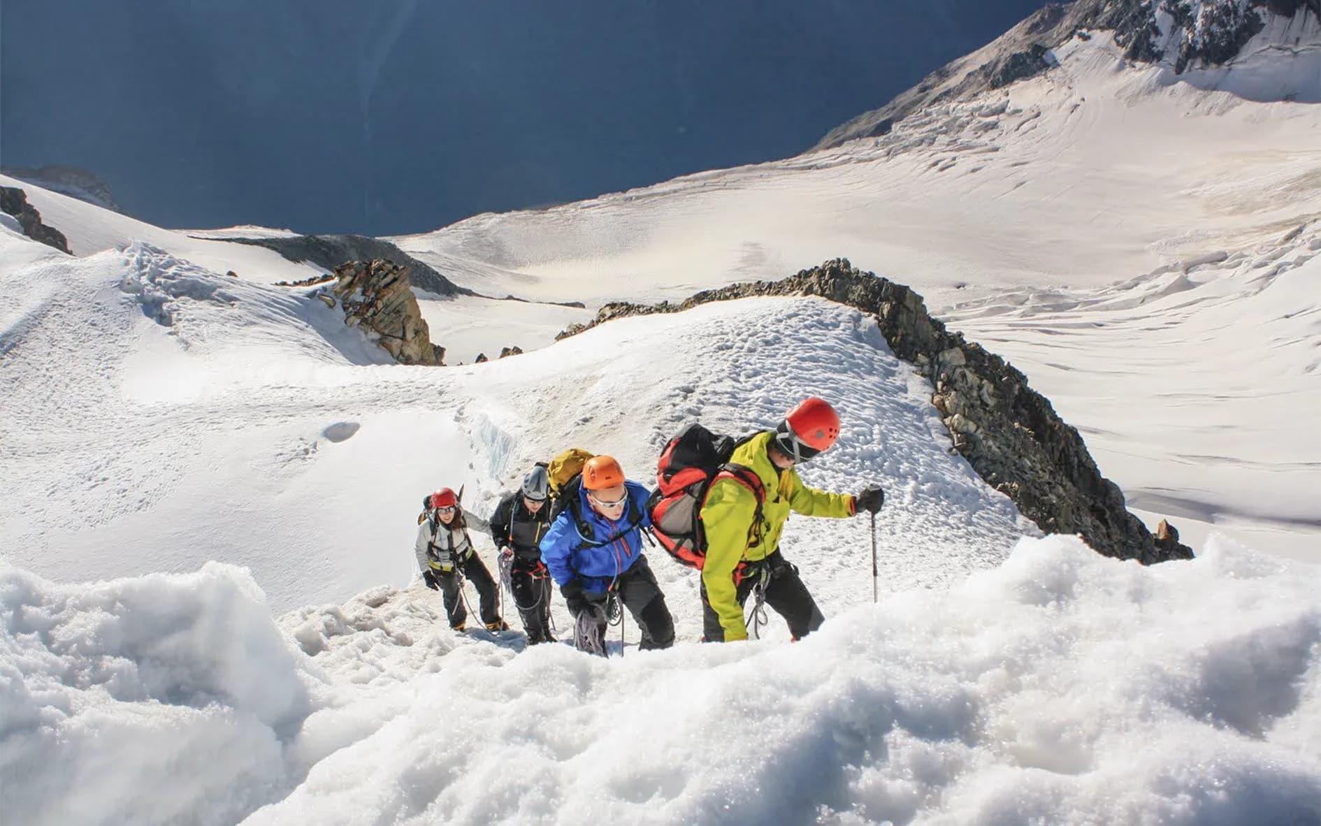 A group of mountaineers climbing a glacier in the sunshine on their way to the summit.