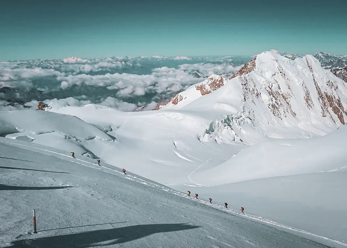 A group of mountaineers skiing on a pristine glacier surrounded by majestic mountains.