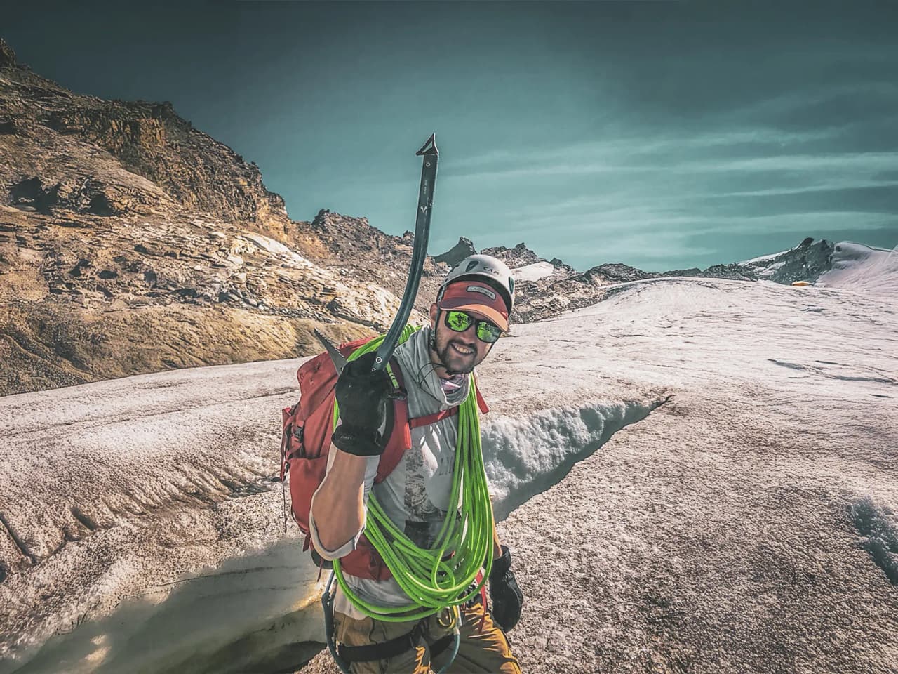 Un alpiniste souriant, piolet à la main, sur un glacier majestueux de Chamonix. Aventure assurée !