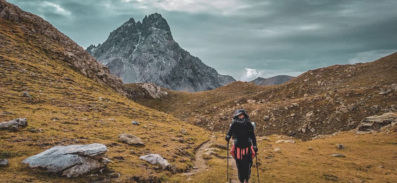 Un randonneur contemplant les majestueuses montagnes des Alpes, nature sauvage et aventure au rendez-vous.