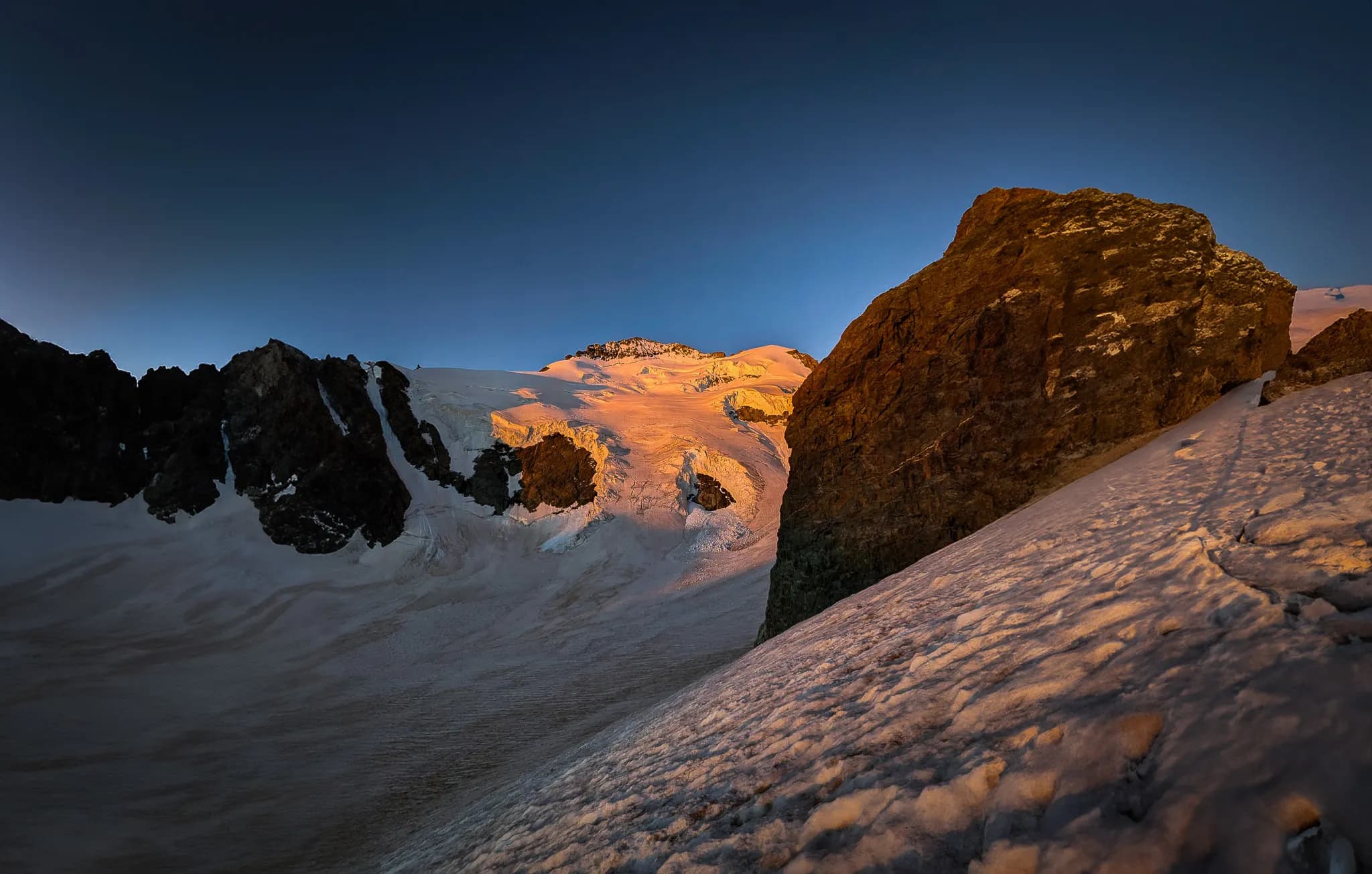 Sublime paysage alpin au lever du soleil, sommets enneigés et rochers majestueux.