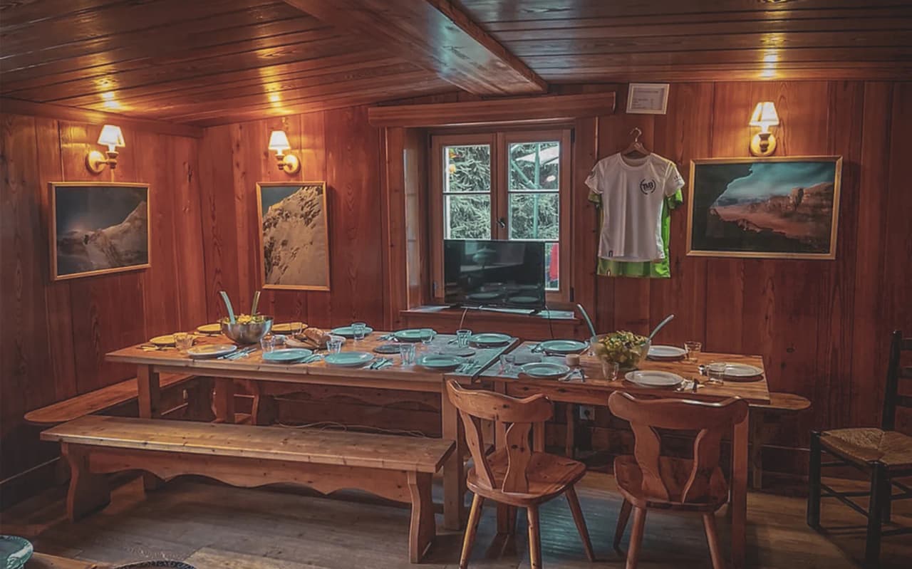 Une salle chaleureuse en bois, prête pour un repas convivial après une journée d'alpinisme.