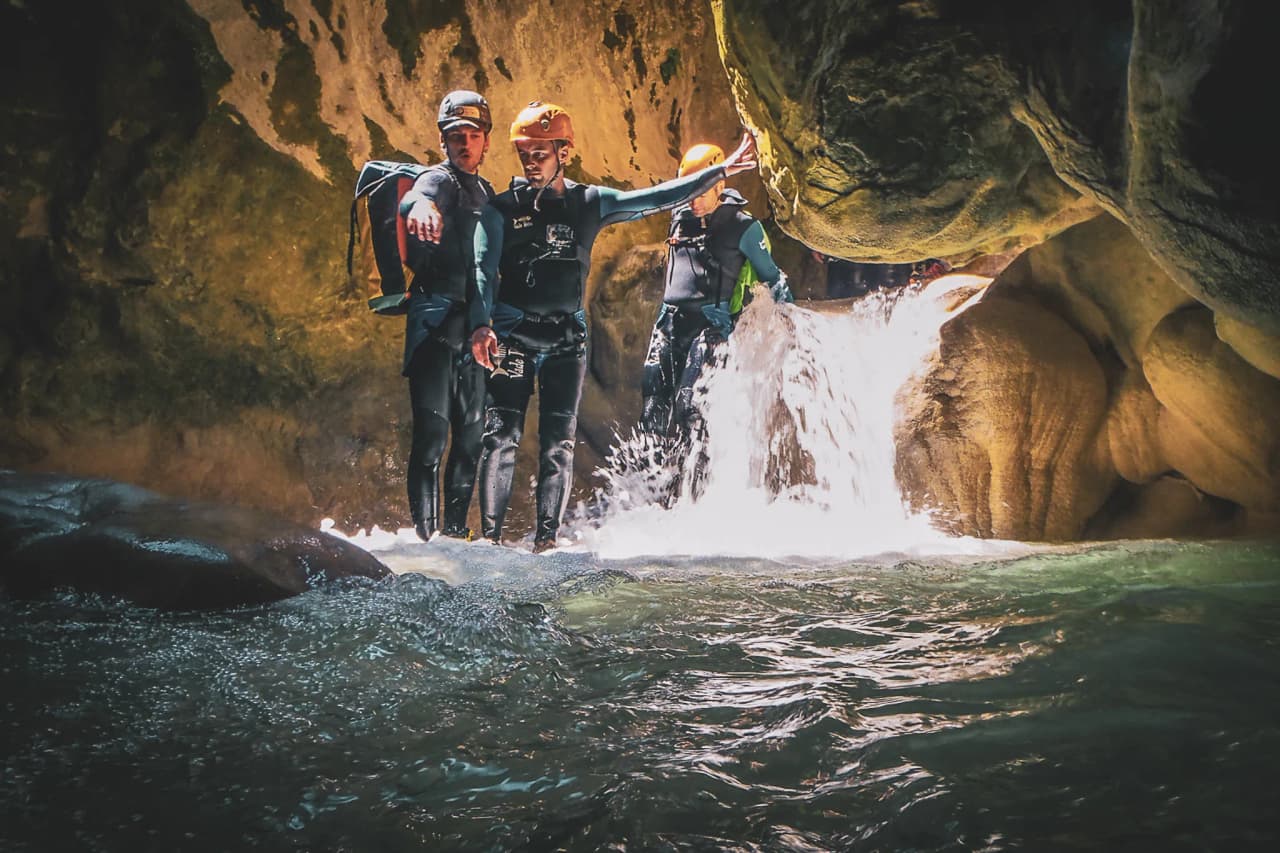Group of adventurers in wetsuits in a canyon, ready for canyoning at the water's edge.