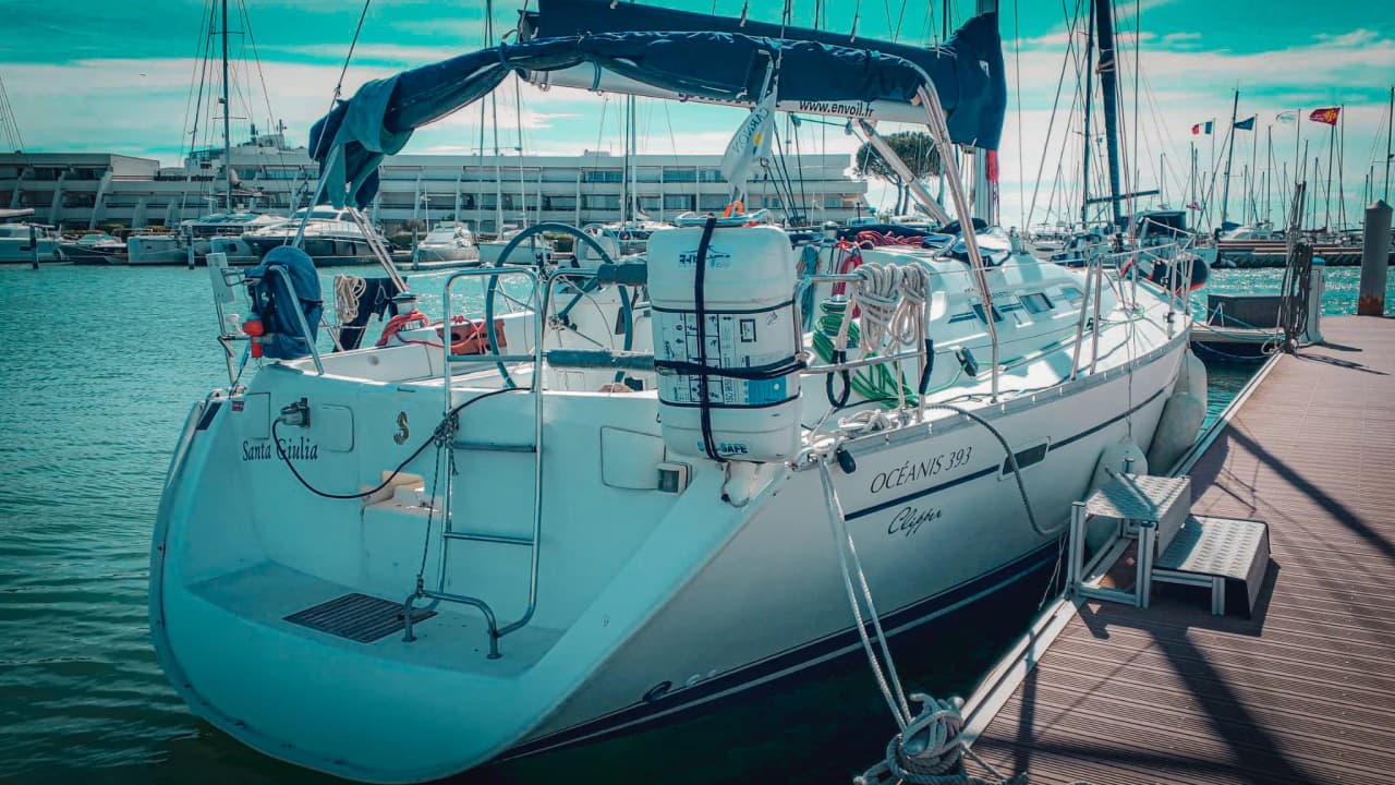 Witte zeilboot aangemeerd in een zonnige mediterrane haven, klaar voor een nautisch avontuur.