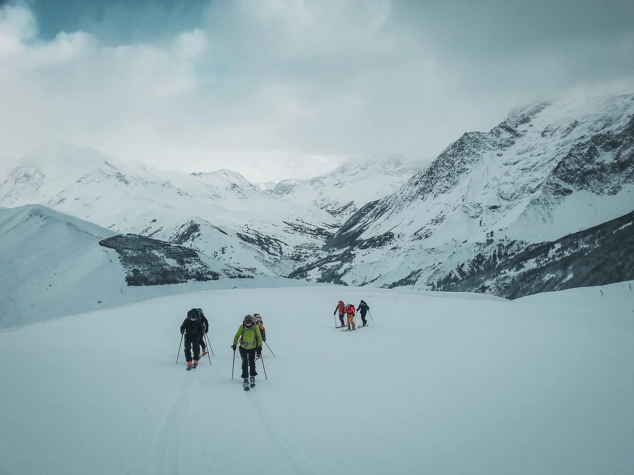 Een groep skitourers baant zich een weg door een majestueus, besneeuwd Alpenlandschap.