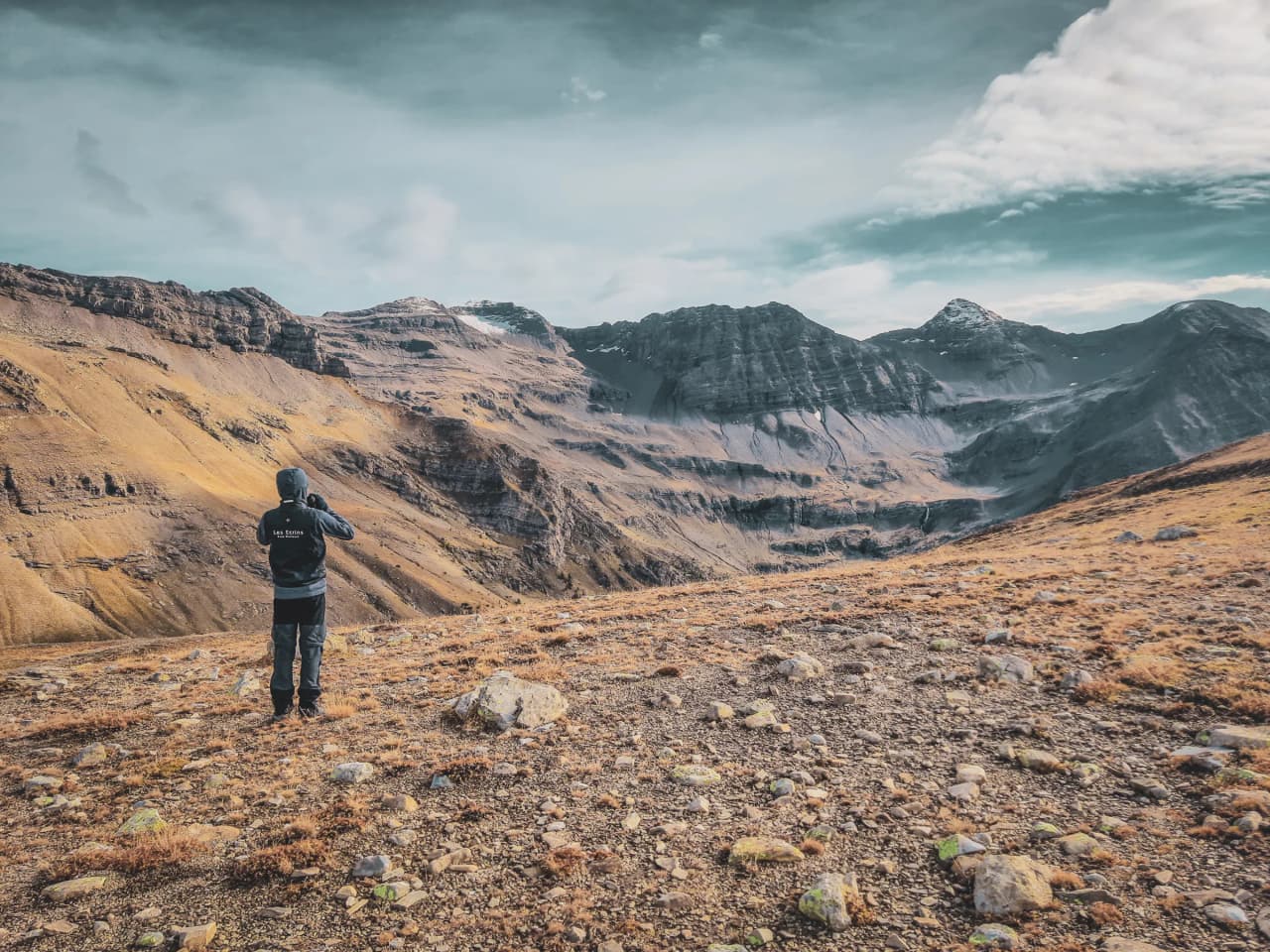 A hiker admires the majestic Écrins mountains, between heaven and earth.