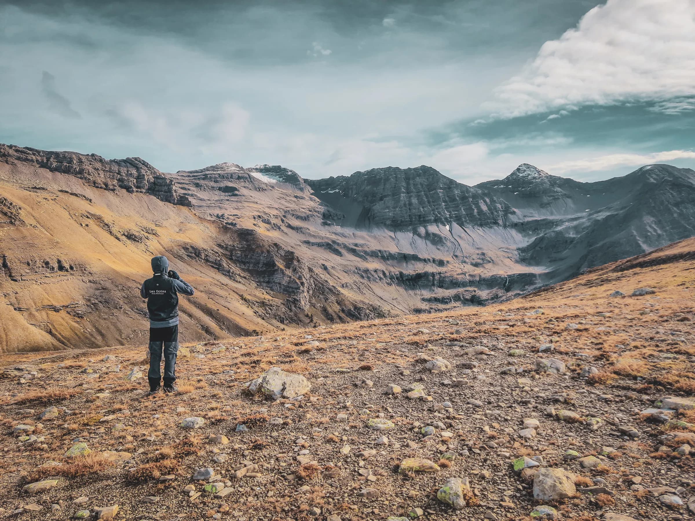 A hiker admires the majestic Écrins mountains, between heaven and earth.