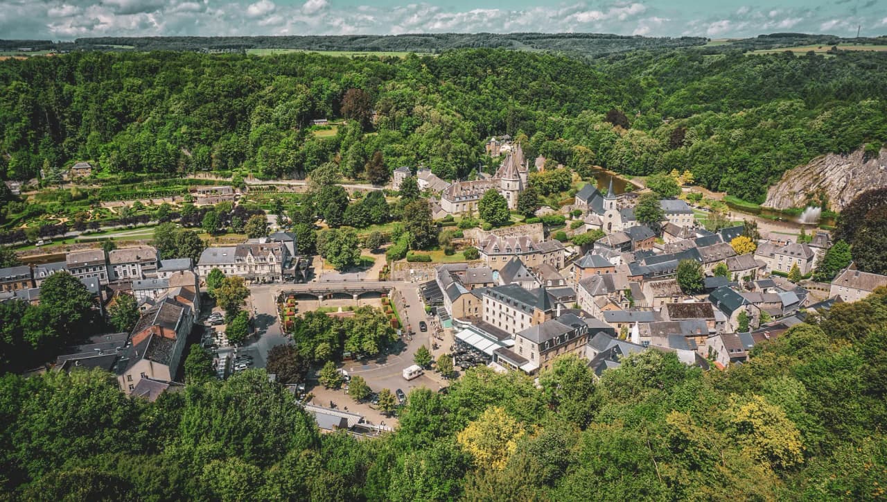 Vue panoramique d'un village pittoresque en Ardenne, entouré de verdure luxuriante.